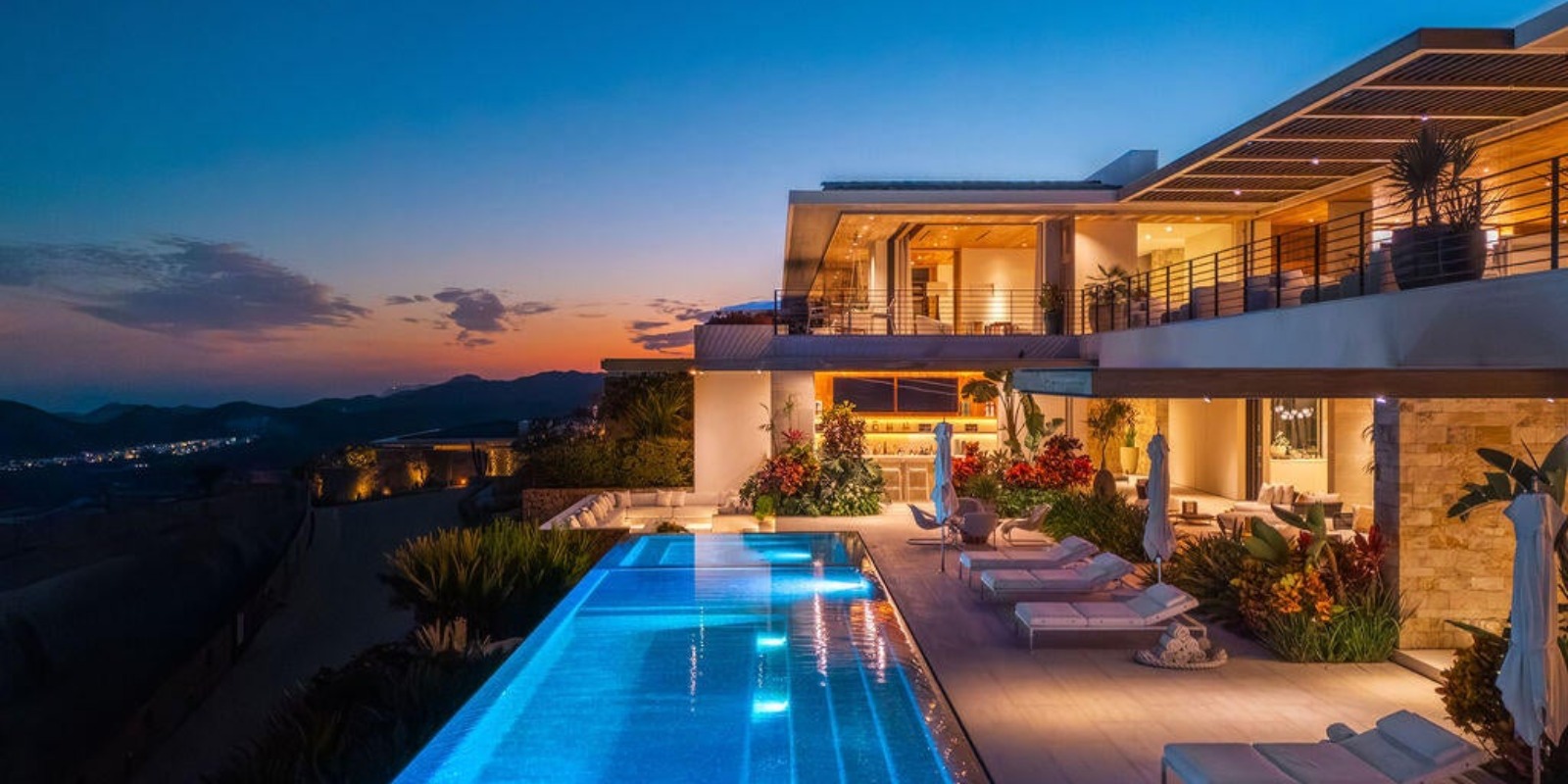 Residencia en Querencia San Jose del Cabo al anochecer, con alberca infinita sobre la ladera y el Mar de Cortes al fondo